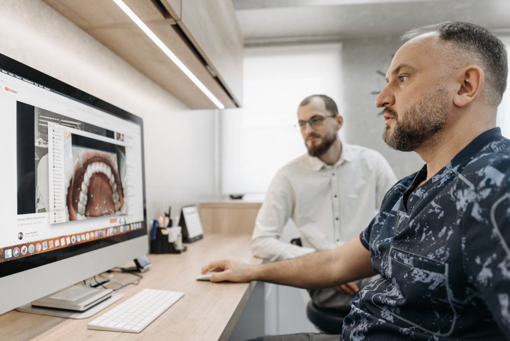 Crafting Captivating Headlines: Your awesome post title goes here Two men discuss dental care at a computer, illustrating modern digital dentistry.